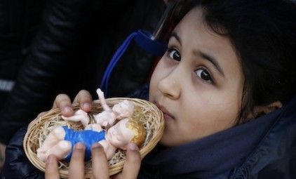 Girl holds baby Jesus figurines for pope to bless during Angelus at Vatican