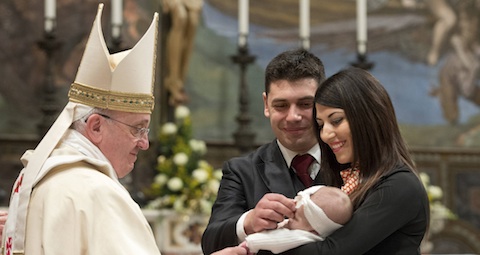 Pope Francis looks over infant during baptisms in Sistine Chapel