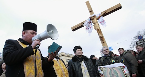 Orthodox clergyman leads prayer service at site where anti-Yanukovich protesters have been killed in recent clashes in Ukraine