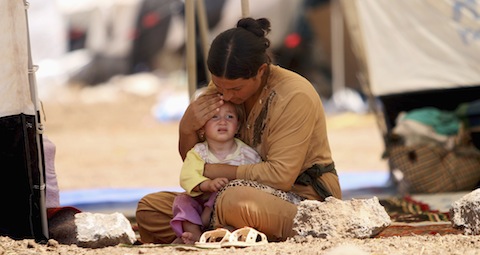 Refugee woman who fled violence in Iraq sits with child at refugee camp in Syria