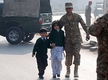 Soldier escorts schoolchildren from Army Public School attacked by Taliban gunmen in Pakistan