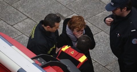 Distressed woman assisted by firefighters after mass shooting at Paris offices of satirical newspaper