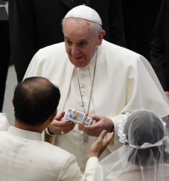 Pope Francis accepts a gift from a newly married couple during his general audience in Paul VI hall at the Vatican Jan. 28. (CNS photo/Paul Haring) See POPE-AUDIENCE Jan. 28, 2015.