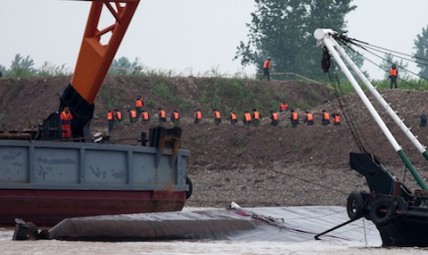 Chinese paramilitary policemen march past the capsized ship, center, on the Yangtze River in central China's Hubei province Wednesday, June 3, 2015. Hopes dimmed Wednesday for rescuing more than 400 people still trapped in a capsized river cruise ship that overturned in stormy weather, as hundreds of rescuers searched the Yangtze River site in what could become the deadliest Chinese maritime accident in decades. (AP Photo/Andy Wong)